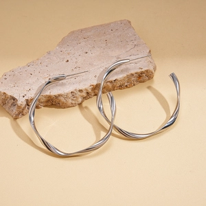Detail of twisted silver geometric earrings on natural stone for a minimalist aesthetic