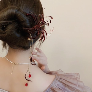Detail of red Lycoris tassel hair stick and pearl necklace on an elegant hair bun