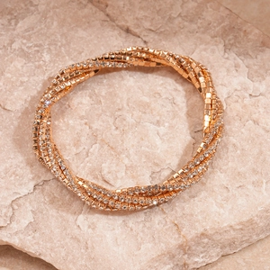 Macro detail of multi-layer rose gold bracelet with sparkling white rhinestones on stone