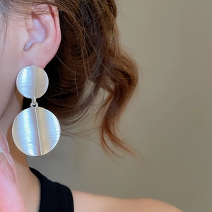 Close-up of model wearing large silver-tone brushed metal round drop earrings