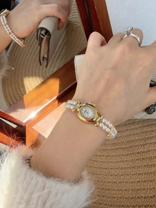 Close-up of vintage gold oval watch with mother-of-pearl dial and pearl strap