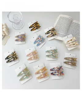Detailed macro view of two marble patterned acetate cat hair clips on a white card