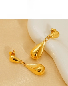 Detailed view of glossy 18K gold teardrop earrings with a smooth polished metallic finish