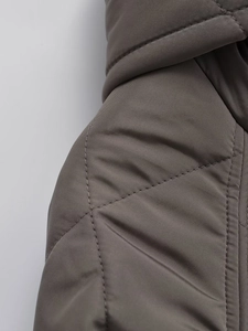 Close-up of dark grey quilted fabric and fine stitching on a long hooded parka