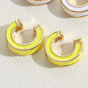 Close-up of C-shaped hoop earrings with bright yellow enamel and gold metallic trim