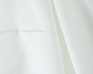 Gros plan sur la texture du tissu blanc montrant les coutures de précision et le fini
