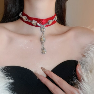 Gros plan du collier choker en velours rouge avec franges en strass et pendentifs