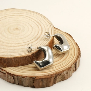 Vue macro de boucles d'oreilles géométriques en acier argenté sur disques de bois