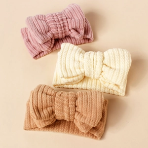 Detailed texture of 3-pack ribbed knit baby headbands with large bows in pink and beige