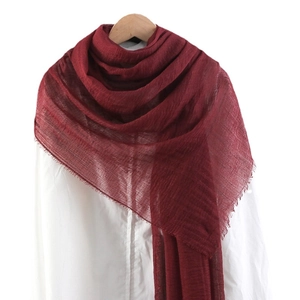 Solid wine red cotton linen scarf with frayed edges and pleated texture on a hanger