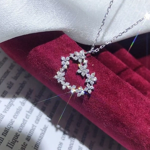 Elegante herzförmige Blumenkette mit weißen Zirkonia auf rotem Samt-Display