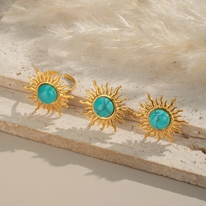 Detail of three vintage sun-shaped gold rings set with turquoise stones on stone