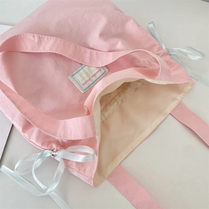 Macro shot of pink canvas tote bag showing inner lining and light blue ribbon bow detail