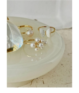 Macro shot of gold-plated rings set featuring elegant pearl clusters and a butterfly motif