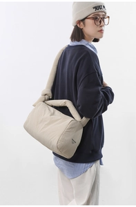 Detail of creamy nylon quilted crossbody bag showing brand logo and soft padded texture