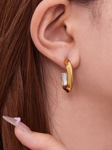 Detailed close-up of U-shaped gold and silver dual-tone polished stainless steel hoop earring