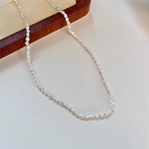 Close-up of small natural baroque freshwater pearl necklace on wooden jewelry tray
