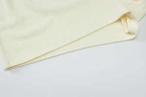 Gros plan sur la maille côtelée crème montrant la couture fine sur l'ourlet arrondi
