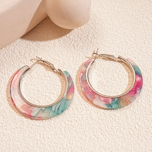 Macro detail of large acetate hoop earrings featuring pink and teal marble texture