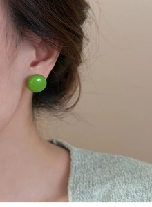 Gros plan d'un mannequin portant des boucles d'oreilles rondes vertes pour un style frais