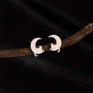 Minimalist silver cat on moon earrings made of stainless steel displayed on a natural branch