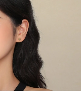 Primo piano di eleganti orecchini floreali vintage dorati indossati da una modella