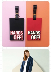 Close-up of PVC luggage tags in red and black with white HANDS OFF! text and leather straps