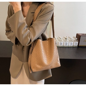 Detail of light brown woven bucket bag showing premium texture and shoulder strap