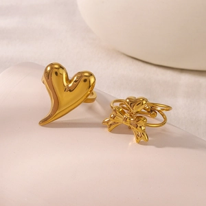 Dettaglio dell'anello a cuore dorato e set con fiocco in acciaio su base bianca