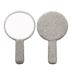Vista detallada de un espejo de maquillaje de mano redondo con diamantes de imitación brillante.
