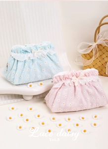 Close-up of floral embroidery and lace trim on a pink and blue fabric makeup bag