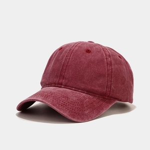 Détail macro de la casquette en coton lavé bordeaux montrant la texture et les coutures