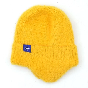 Detailed close-up of yellow knit winter hat with blue snowflake tag and soft plush lining