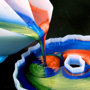 Detailed view of 3-slot silicone split cup pouring colorful epoxy resin into gear mold