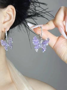 Detail view of purple zircon butterfly hoop earrings worn on ear to show size and sparkle