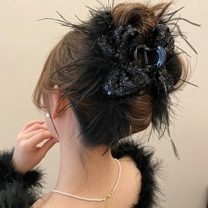 Detail of black feather bow hair claw clip styled in an elegant updo for women