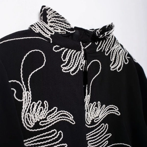 Black high collar blouse with white embroidery detail and elegant ruffled neckline