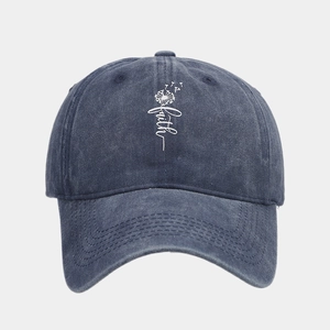 Detail of dark blue washed denim baseball cap with faith print and dandelion pattern