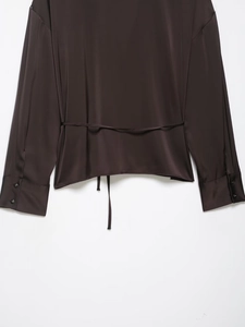 Detail view of smooth satin fabric and thin back waist belt on a dark brown shirt
