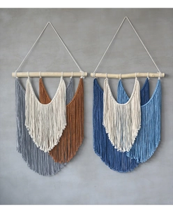 Détail de tapisseries murales bohèmes tissées main avec franges sur tiges en bois