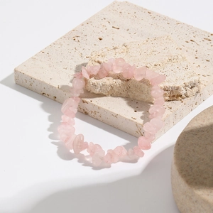 Detail of bohemian natural pink quartz crystal elastic bracelet on beige stone plates