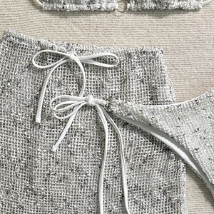 Close-up of white knit beach cover-up featuring intricate crochet texture and drawstring