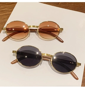 Detalle de gafas de sol ovales con montura dorada y patillas con textura de madera café