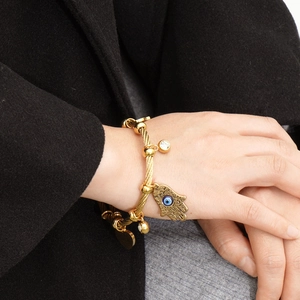 18K gold Hamsa Hand and Evil Eye cable wire bracelet worn with a stylish outfit
