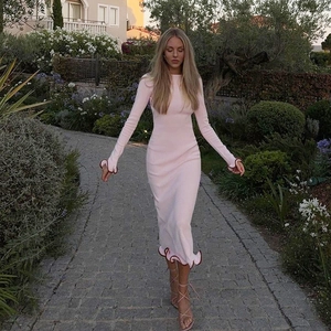 Detalle del vestido de punto rosa con bordes ondulados rojos en un jardín