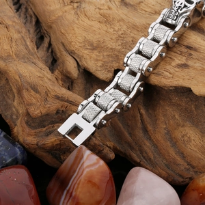 Detailed macro of motorcycle chain steel bracelet with gothic skull and dark wood background