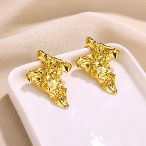 Detailed macro view of gold petal earrings with artistic lava texture on ceramic