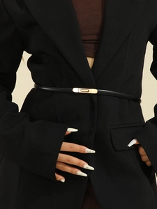 Detail of slim black patent leather belt with a rectangular gold buckle on a black blazer