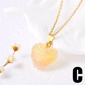 Détail d'un pendentif cœur à facettes sur une chaîne dorée avec de jolies fleurs séchées
