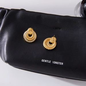 Macro shot of 18k gold plated fan-shaped earrings with zircon inlay on black leather